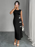Woman taking a mirror selfie wearing a black slit dress with white bow details against a gray wall.