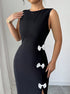 Black dress with white bow details worn by a woman against a neutral background