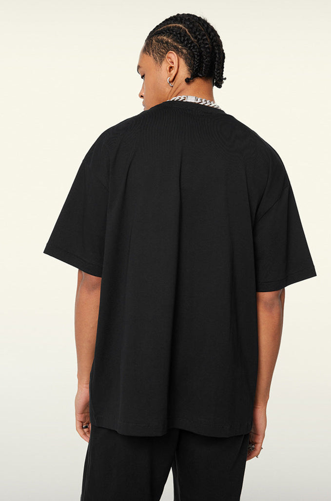 Back view of male model in plain black oversized T-shirt, hands relaxed at sides.