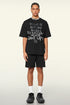Male model in black oversized T-shirt and shorts with motivational quote, standing in neutral pose.
