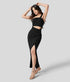 Black one-shoulder maxi dress with draped bodice, waist cut-out, and thigh slit shown in dynamic full-body pose.