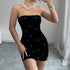 Close-up of black velvet bodycon mini dress featuring pearl embellishments and strapless neckline.