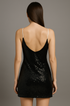 Back view of black sequin dress worn by a model on a plain background
