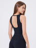 Back view of woman in black athletic tank top with open back and matching leggings.