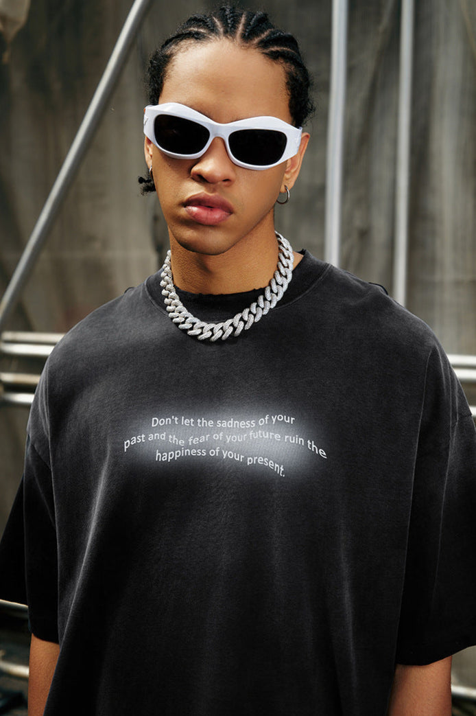 Close-up of man wearing black quote tee, white sunglasses, and thick silver chain.