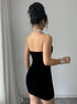 Back view of black velvet bodycon mini dress with smooth strapless design and hip-hugging fit.