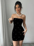 Black velvet bodycon mini dress with pearl embellishments and strapless neckline front pose.