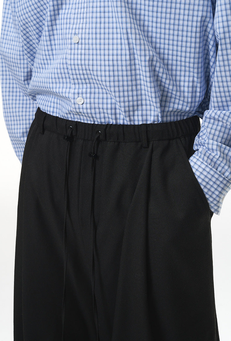 Close-up of black wide-leg trousers with elastic waistband and drawstring