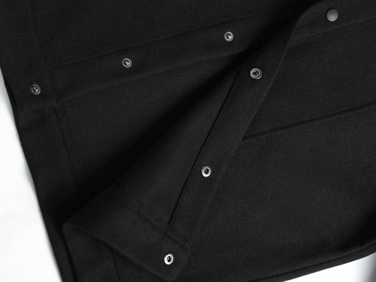 Close-up of a black wool jacket with button details on a white background