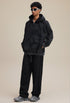 Model full outfit in black zip hoodie and pants, oversized fit, side view. 