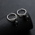 Pair of silver hoop earrings with black zircon charms on textured display.