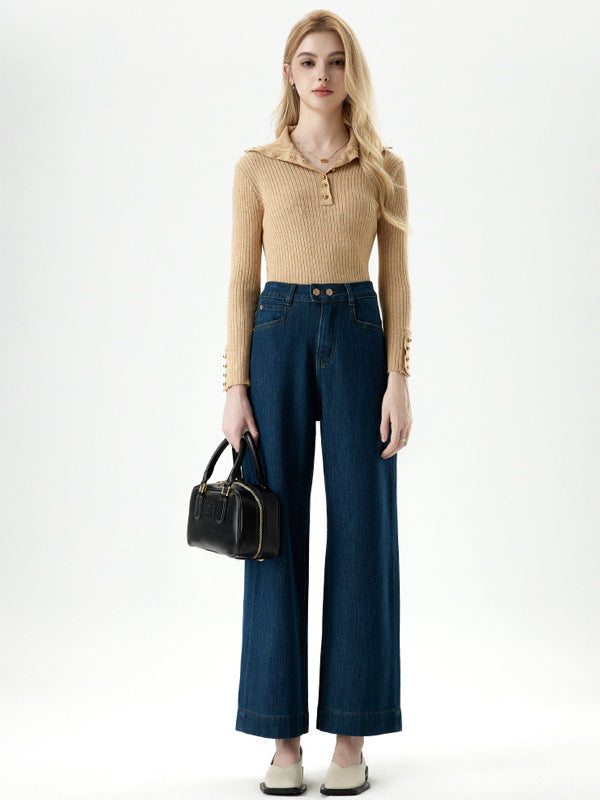 Model standing in beige ribbed sweater and dark blue wide leg cropped jeans.