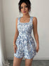 Woman wearing a blue floral romper against a plain background