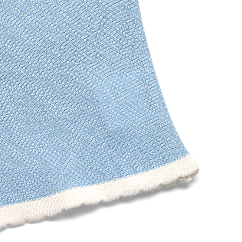 Hem detail of blue knit cami with white scalloped trim and textured fabric.