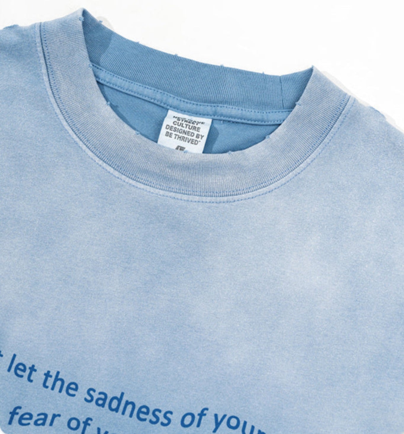 Close-up of blue gradient tee neckline showing inner label with brand name.