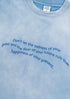 Close-up of quote print on blue gradient tee with soft fabric texture.