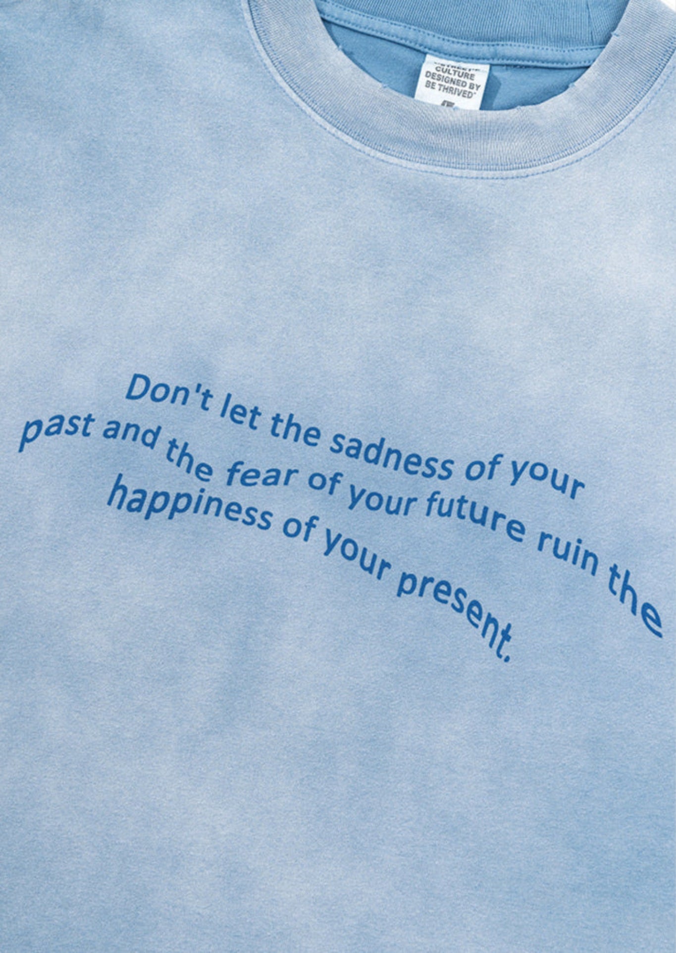 Close-up of quote print on blue gradient tee with soft fabric texture.