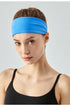 Woman wearing a wide bright blue headband and black sports top, front view.