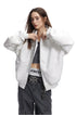 Front view of a model wearing a heather light grey boxy zip up hoodie open over a grey tank top and dark jeans.