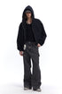 Full body view of a male model in a black boxy zip up hoodie, cap, black tank top, and wide-leg cargo pants.