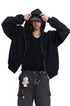 Medium shot of a male model adjusting cap while wearing a black boxy fit zip up hoodie.