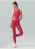 Full-body view of woman in brick red high-neck crop top and leggings, standing with one leg raised.