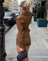woman wearing brown suede jacket photographed from behind on sidewalk