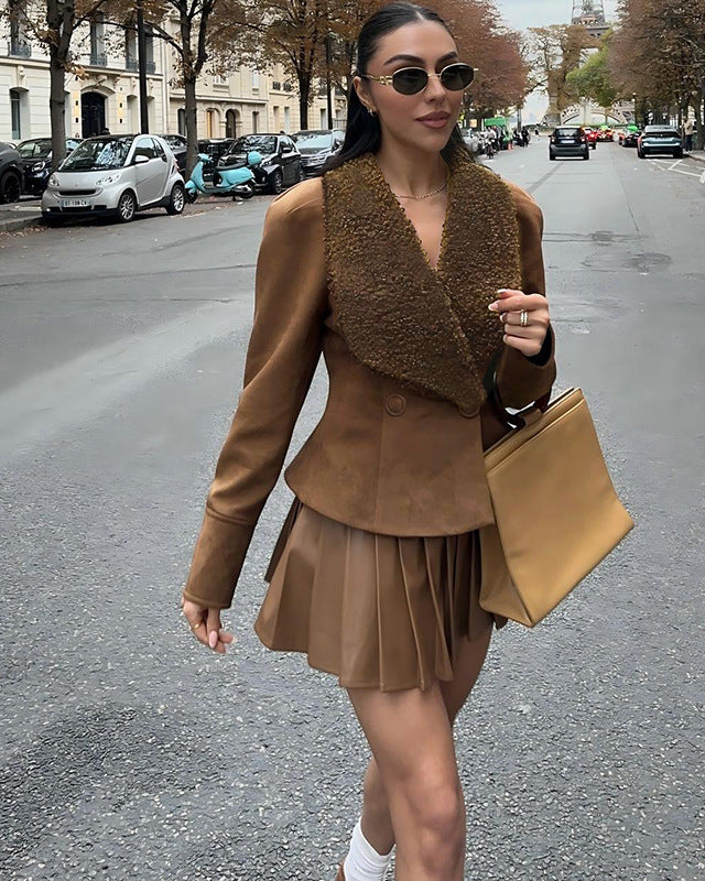 woman walking on street wearing brown suede jacket and pleated skirt