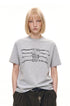 Model wearing a heather gray chain graphic T-shirt with dark wide-leg trousers