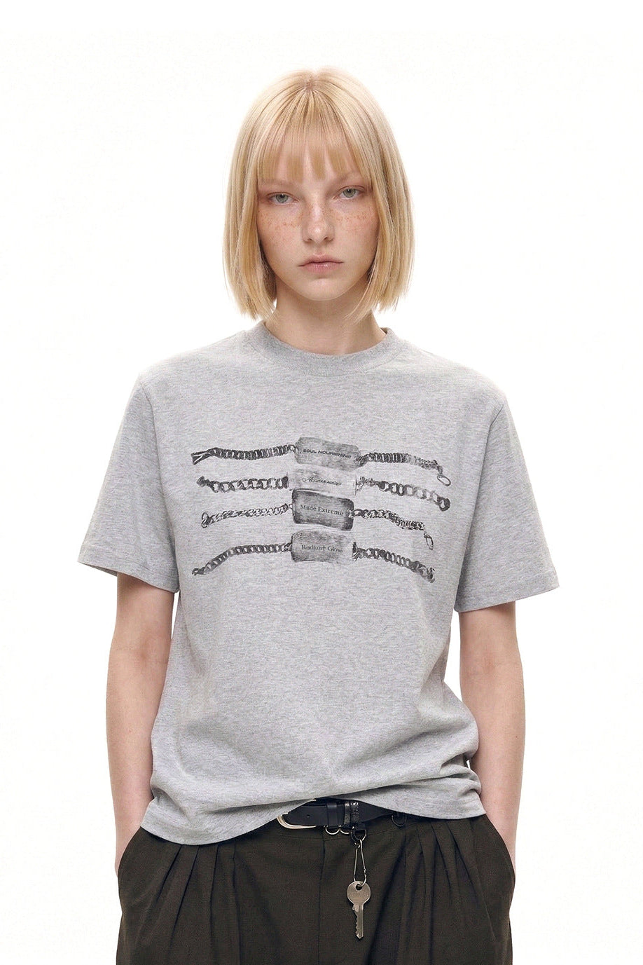 Model wearing a heather gray chain graphic T-shirt with dark wide-leg trousers