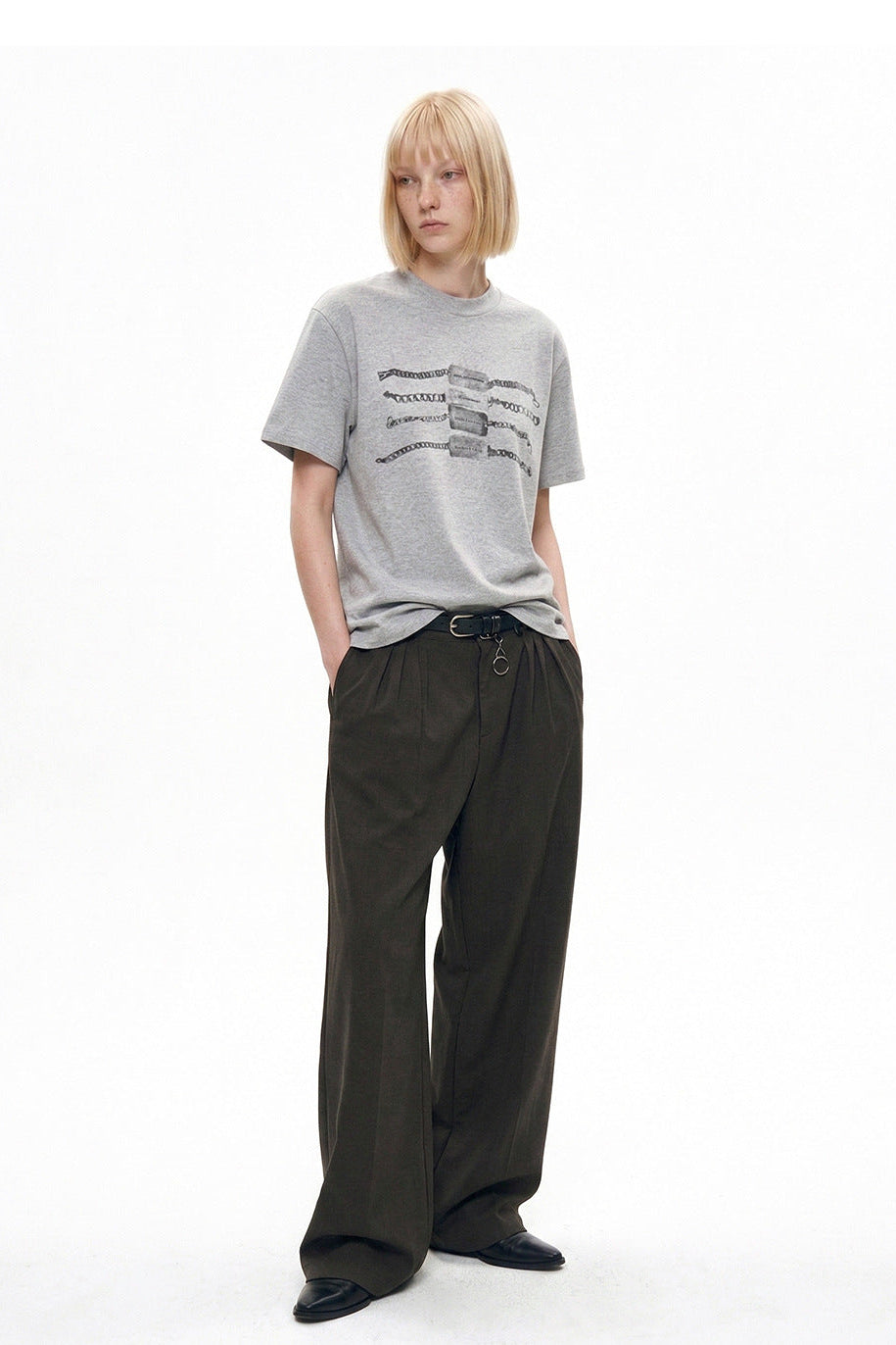 Three-quarter view of heather gray chain graphic T-shirt styled with pleated trousers