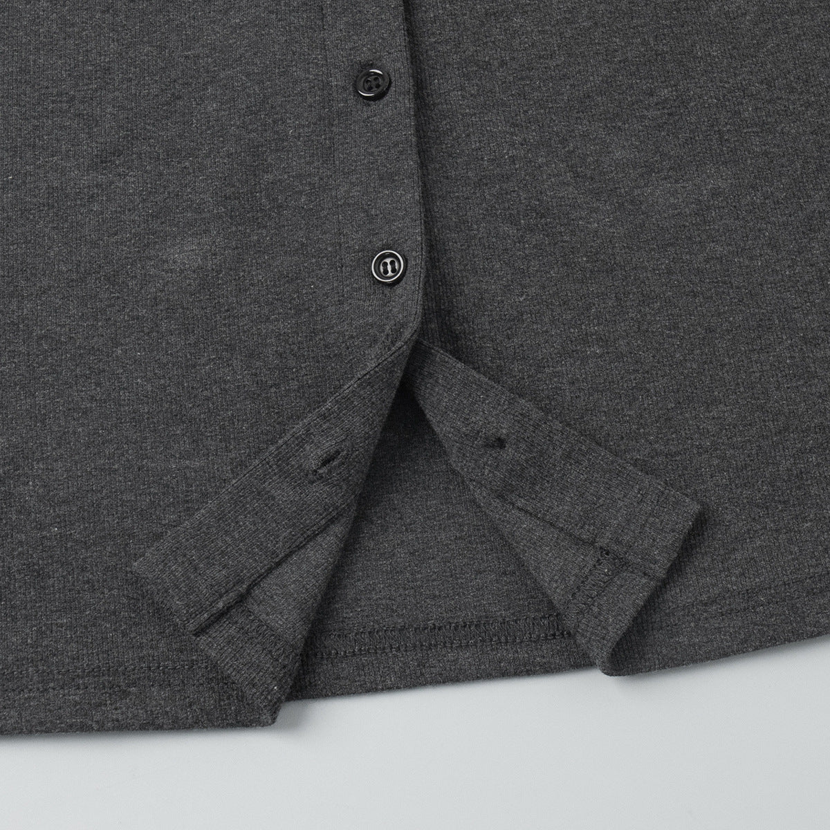 Close-up of a charcoal cardigan's buttons on a light gray background