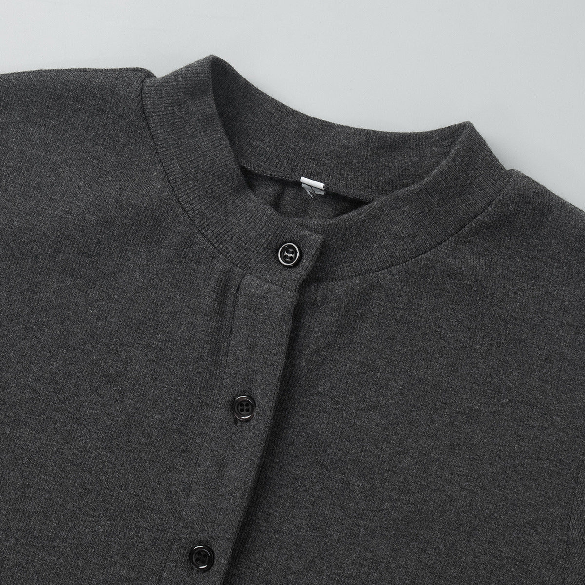 front view of charcoal ribbed crop cardigan laid flat showing button closure