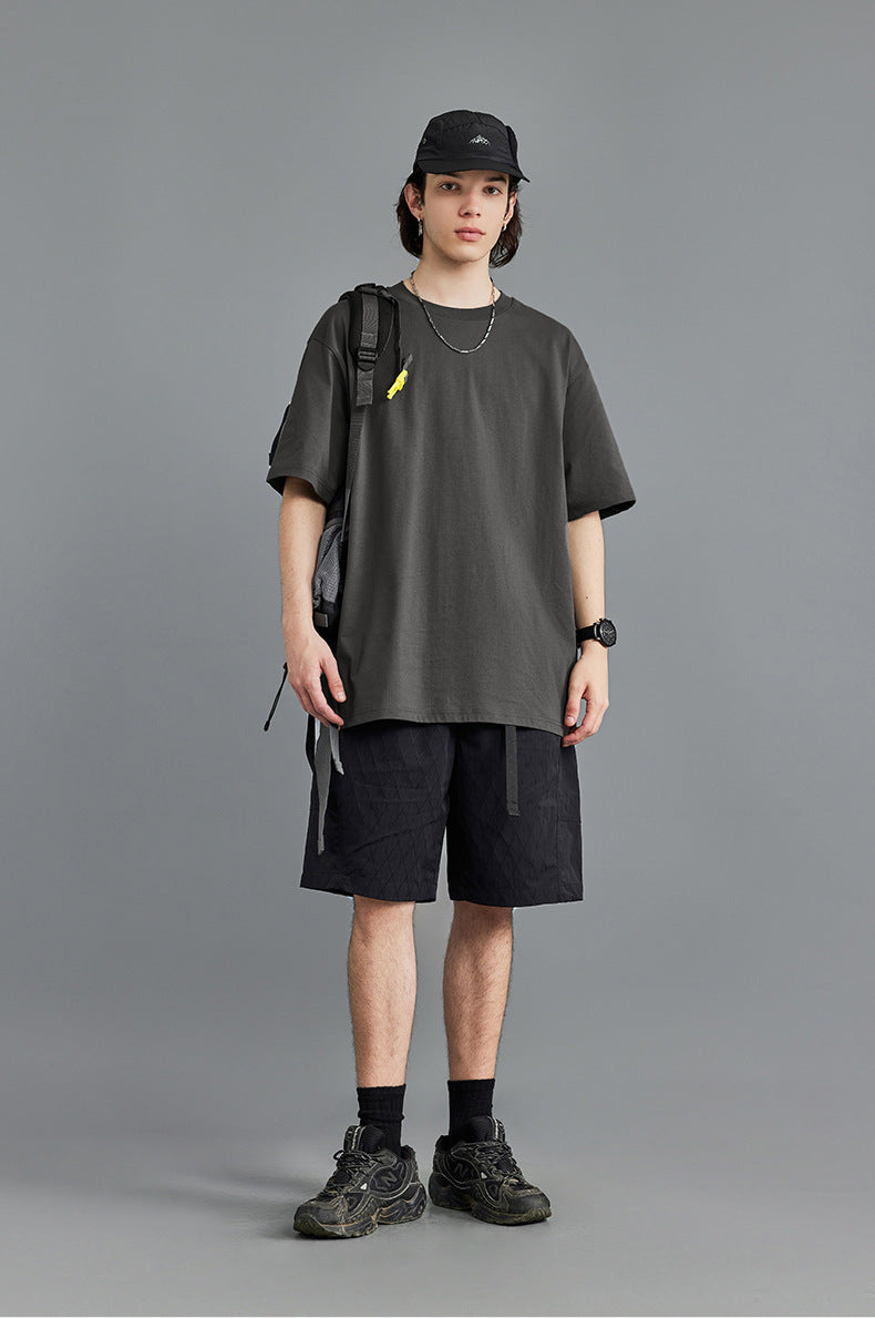 Male model in charcoal gray oversized tee with black cap, studio backdrop
