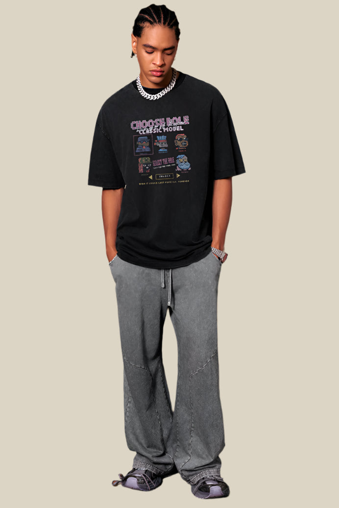 Man leaning with hands in pockets, wearing oversized black pixel graphic tee