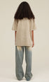 Woman in khaki tee and ombré jeans, back facing camera with voluminous curls
