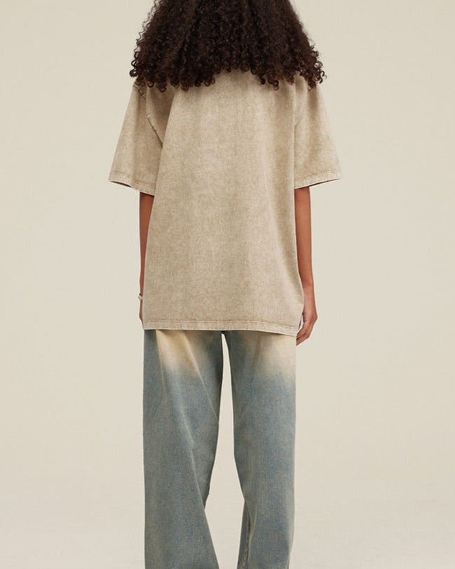 Woman in khaki tee and ombré jeans, back facing camera with voluminous curls