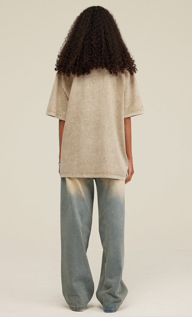 Woman in khaki tee and ombré jeans, back facing camera with voluminous curls