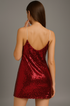 Back view of a claret sequin dress worn by a model on a gray background