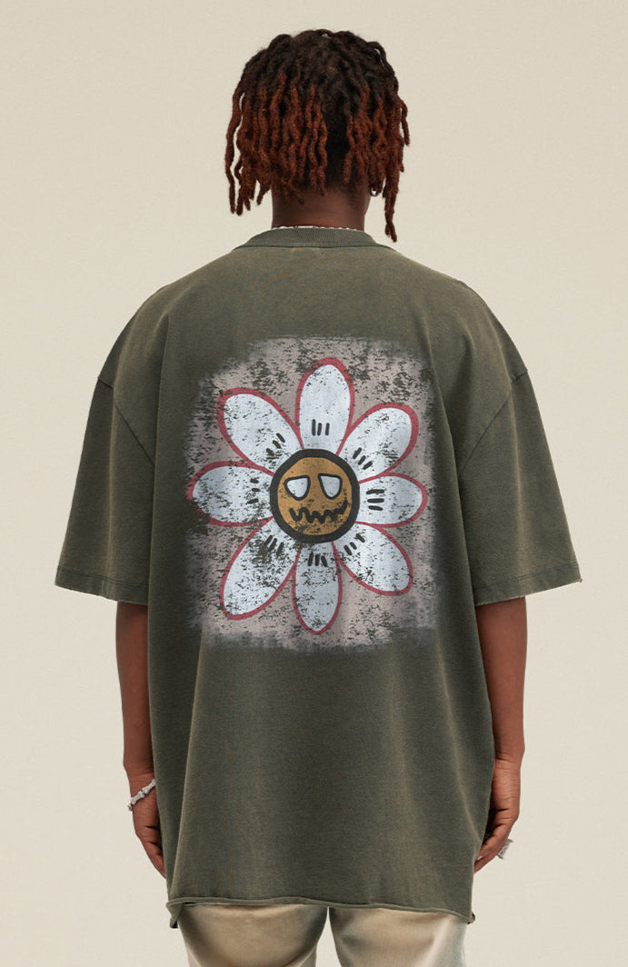 Back close-up of daisy graphic with expressive face on olive green t-shirt.