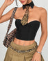 Woman posing in a black corset top, leopard accessories, and pleated khaki skirt.