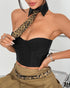 Woman wearing a black strapless corset top with a leopard tie and khaki pleated skirt.