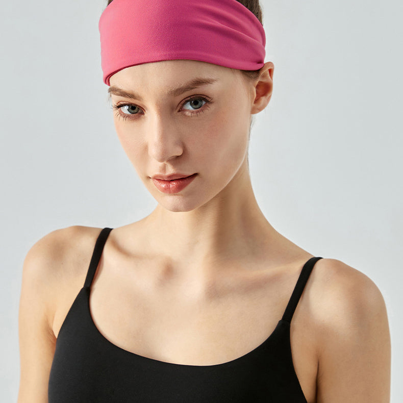 Woman wearing a wide cranberry headband and black sports top, front view.