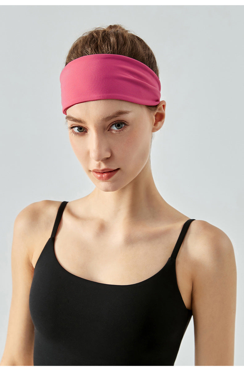 Woman wearing a wide cranberry headband and black sports top, front view.