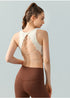 Back view of cream strappy open-back sports bra paired with brown leggings.