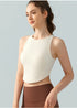 Woman in cream high-neck crop top and brown leggings, facing slightly to the side.
