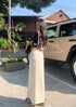 Model poses in sunlight wearing cream maxi skirt with side pocket and cropped camo top.