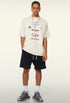 Model in cream t-shirt with black shorts and grey sneakers