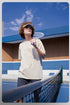 Unisex cream tee styled casually on a tennis court rail