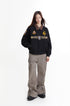 Model wearing black embroidered Detroit jacket with wide gray cargo pants